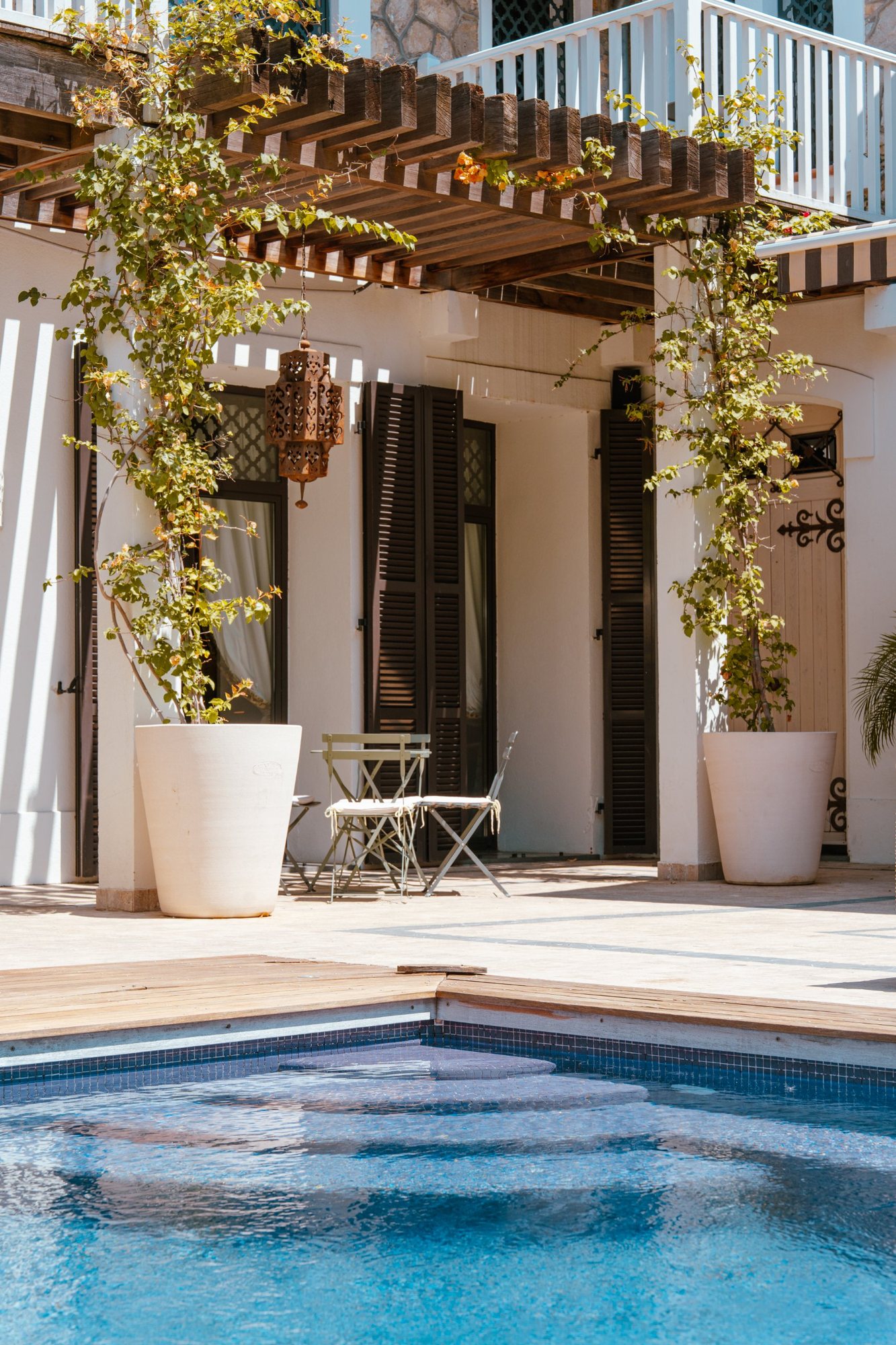 Photographe d’espaces extérieurs en Alsace : pergola, bougainvilliers et piscine devant une façade blanche