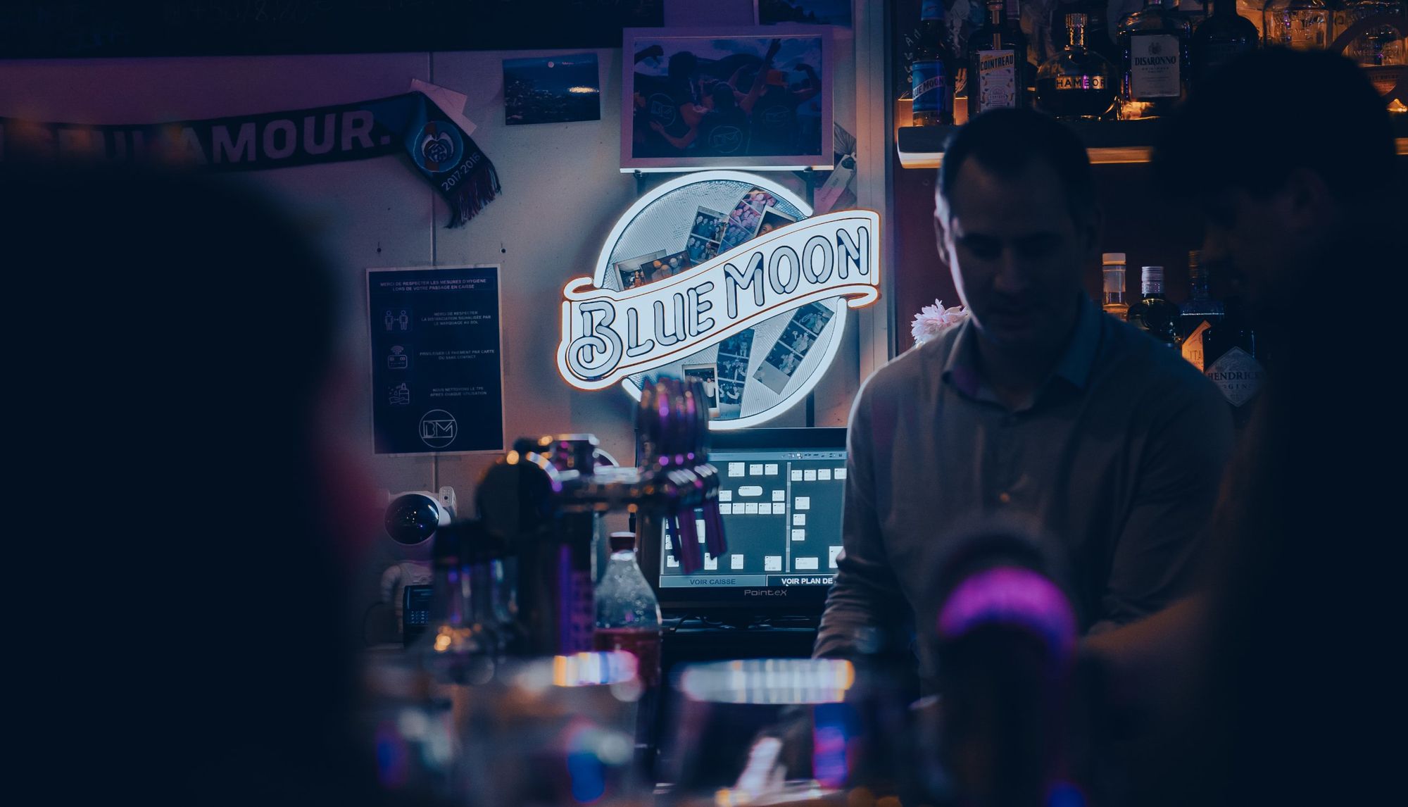 Photographe de soirée à Strasbourg : ambiance de bar avec néon Blue Moon et barman