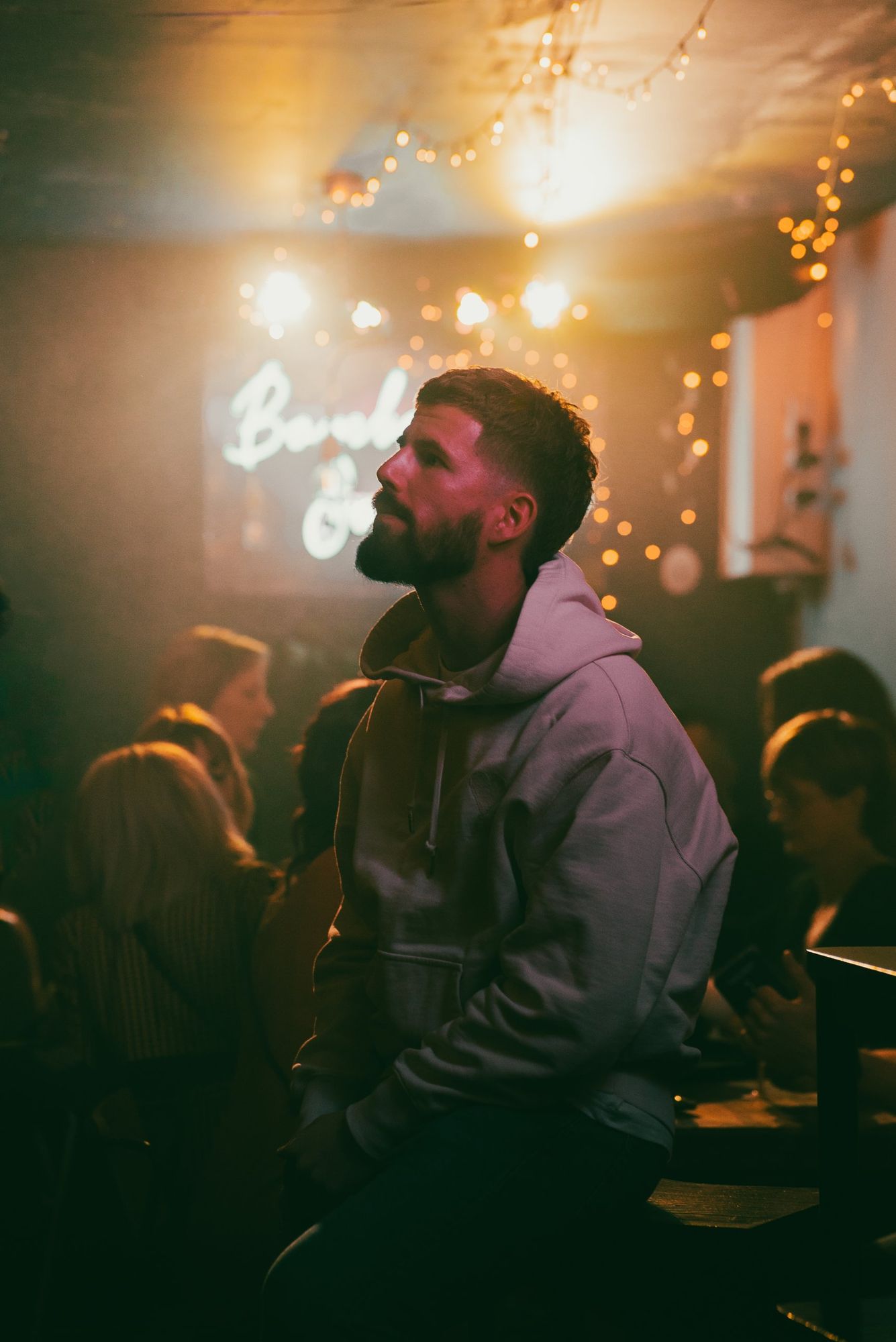 Photographe événementiel en Alsace : portrait d’un homme en sweat à capuche dans un bar chaleureux