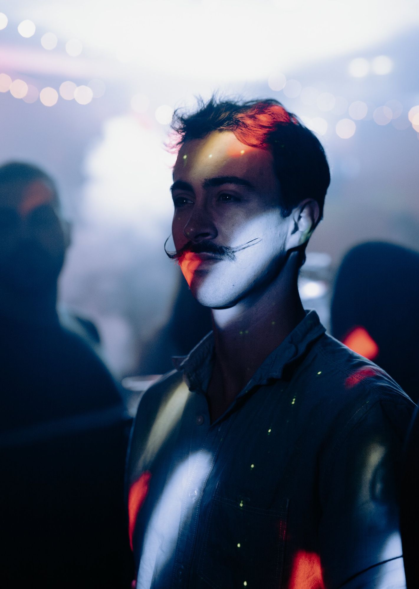 Photographe de soirée à Strasbourg : portrait d’un homme à moustache éclairé par des projecteurs colorés