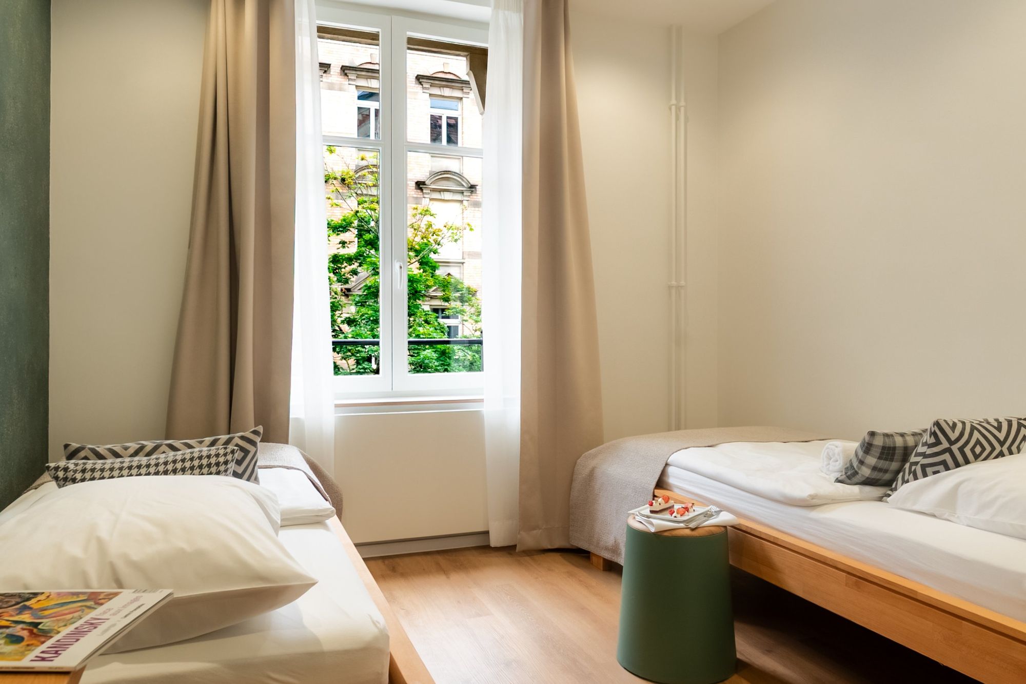 Photographe immobilier et hôtel à Strasbourg : chambre à deux lits donnant sur un arbre en fleurs