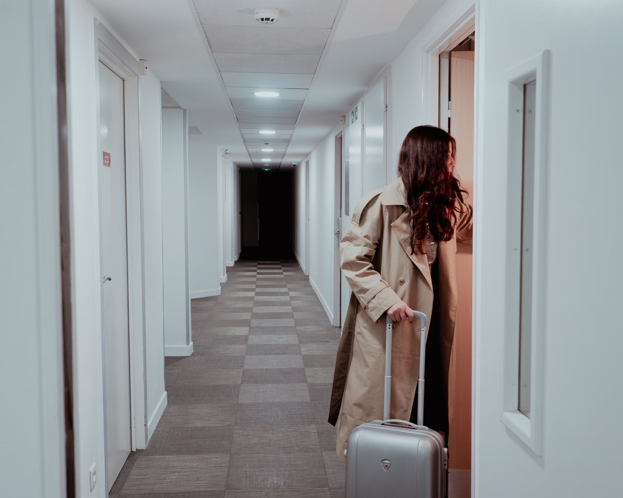 Photographe d’hôtel à Strasbourg : cliente avec sa valise ouvrant la porte de sa chambre dans le couloir