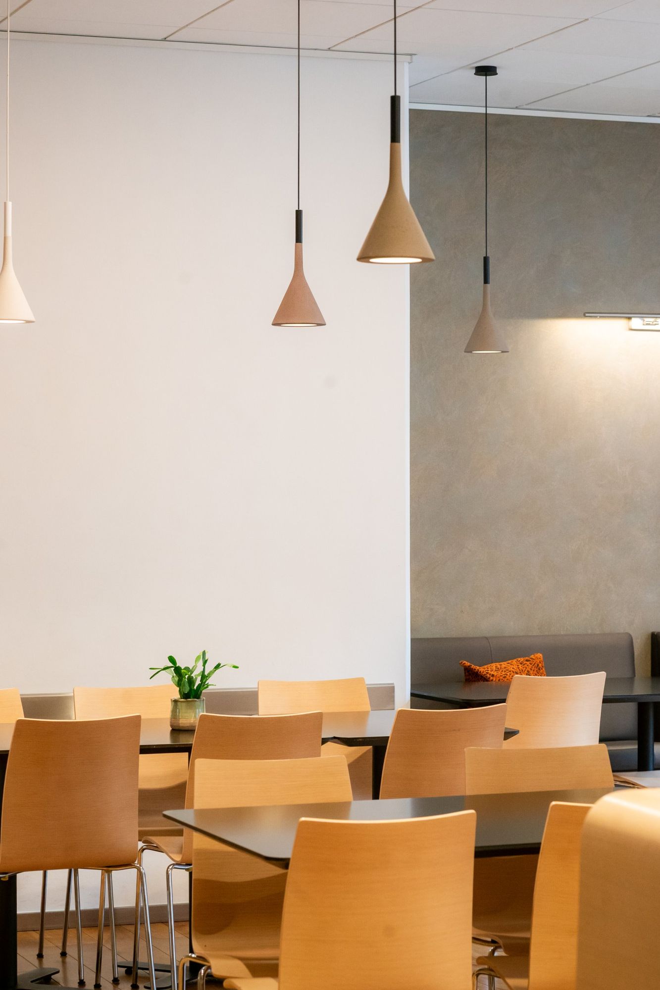 Photographe d’hôtel à Strasbourg : salle de restaurant lumineuse, suspensions en béton et chaises en bois