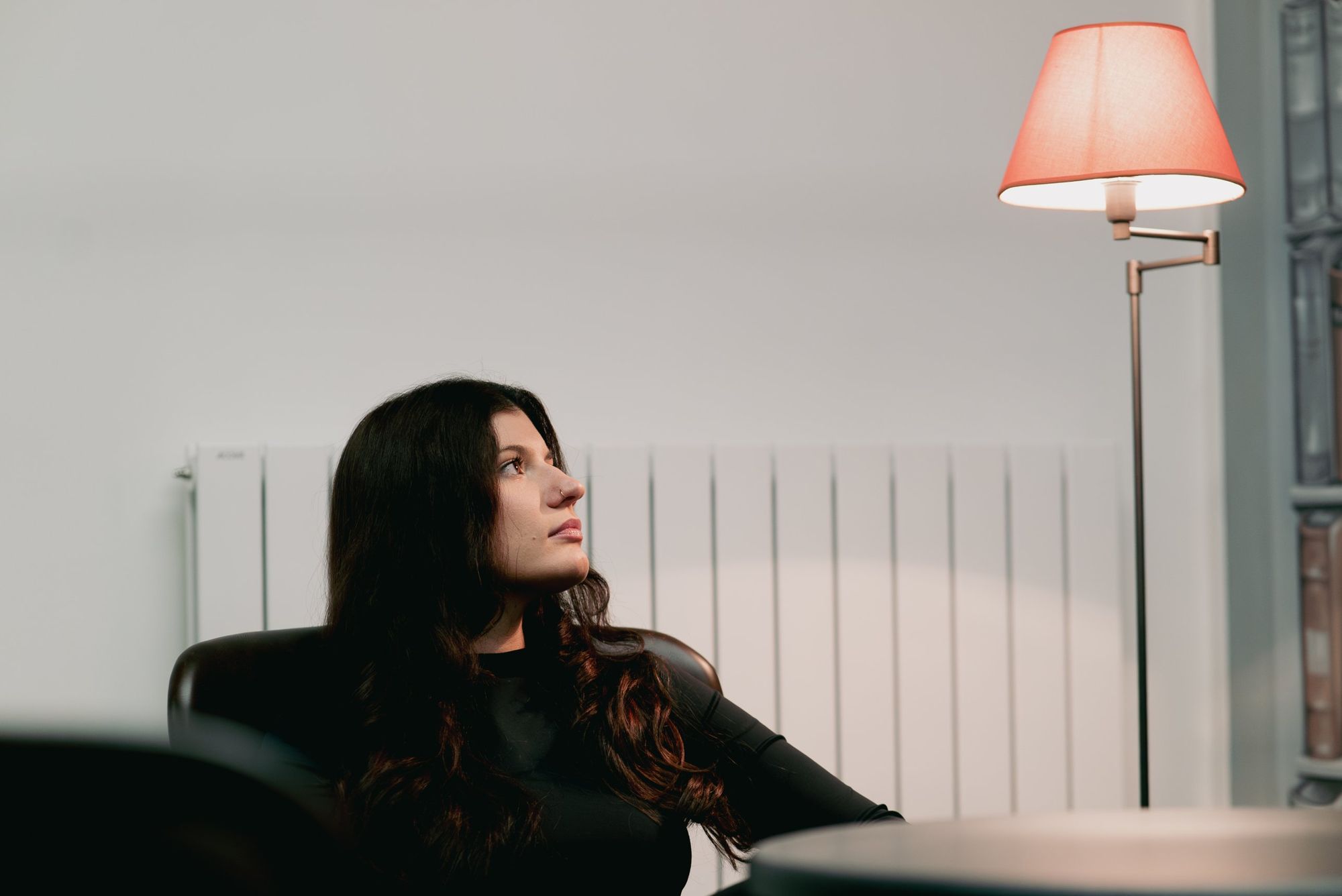 Photographe d’hôtel en Alsace : portrait d’une femme dans le salon, lampe orangée au premier plan