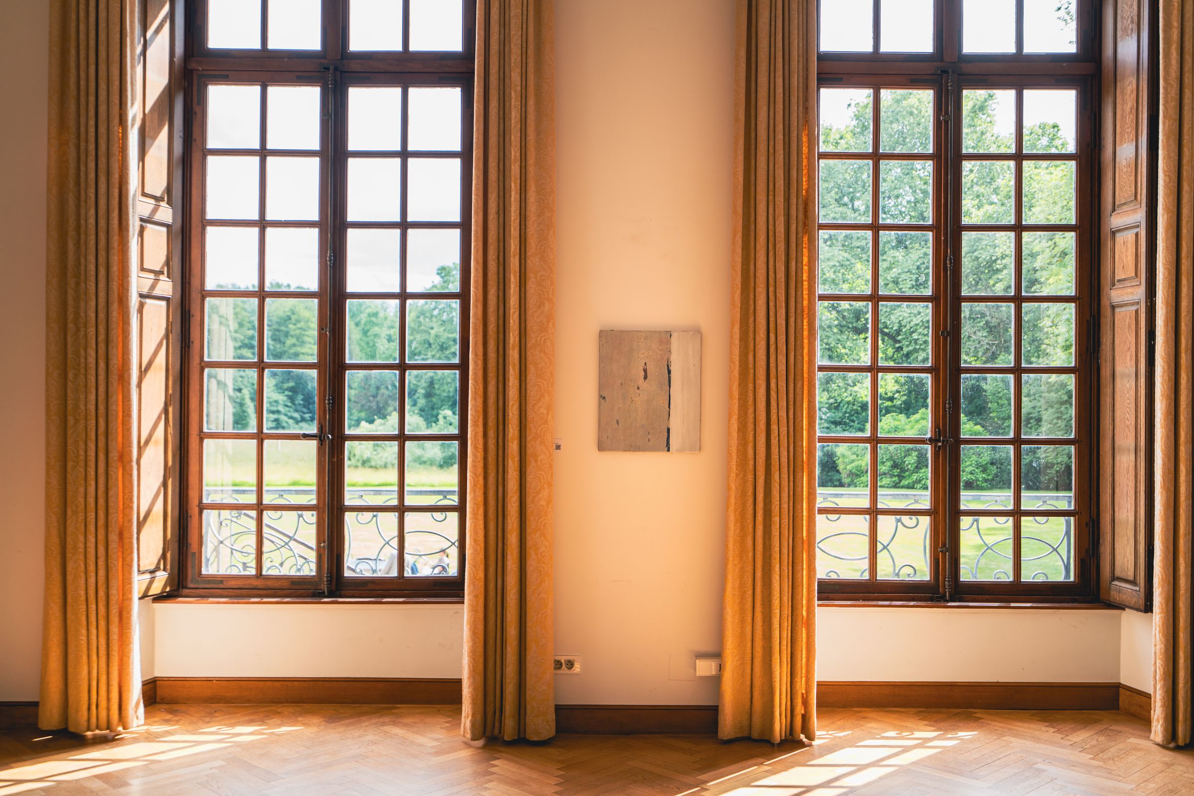 Photographe d’intérieur à Strasbourg : grande salle lumineuse aux hautes fenêtres, rideaux et parquet en point de Hongrie