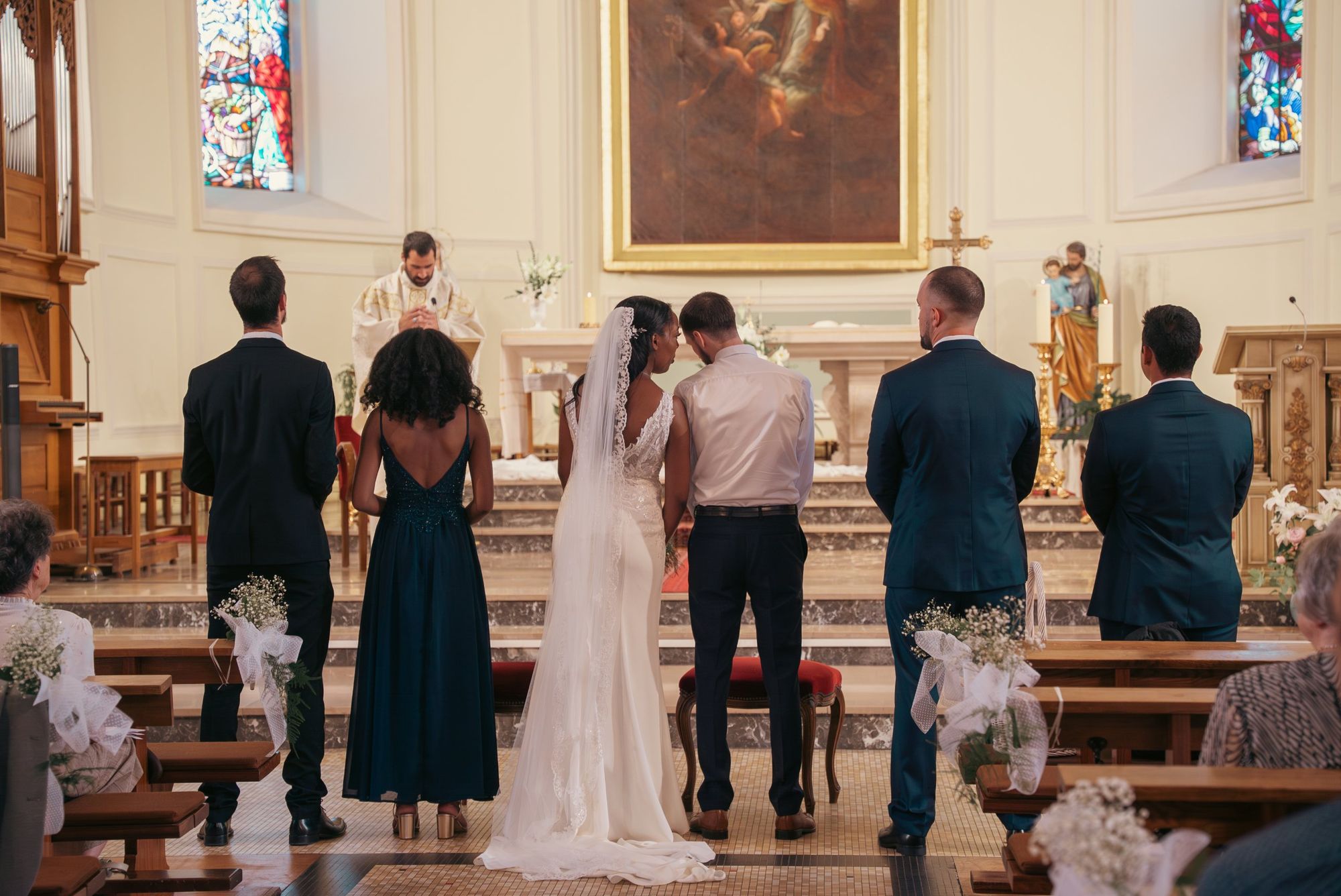 Vidéaste de mariage en Alsace : les mariés de dos devant le prêtre pendant la cérémonie à l’église