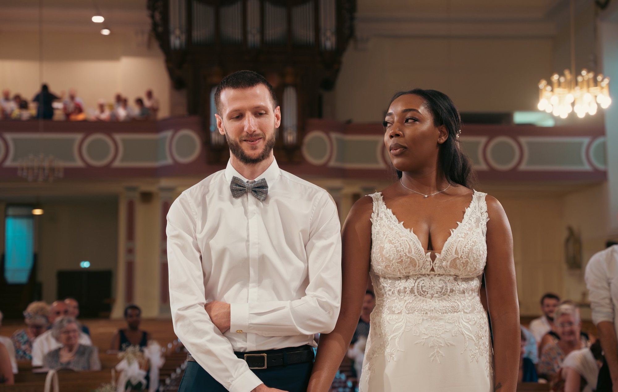 Photographe de mariage en Alsace : les mariés devant l’autel pendant la cérémonie à l’église, orgue et invités en arrière-plan