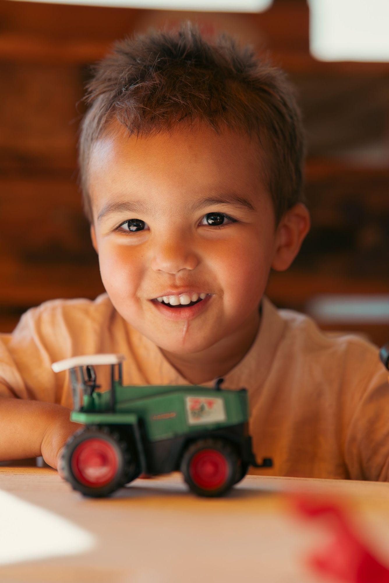 Photographe de mariage en Alsace : portrait d’un petit garçon souriant avec son tracteur jouet pendant la réception