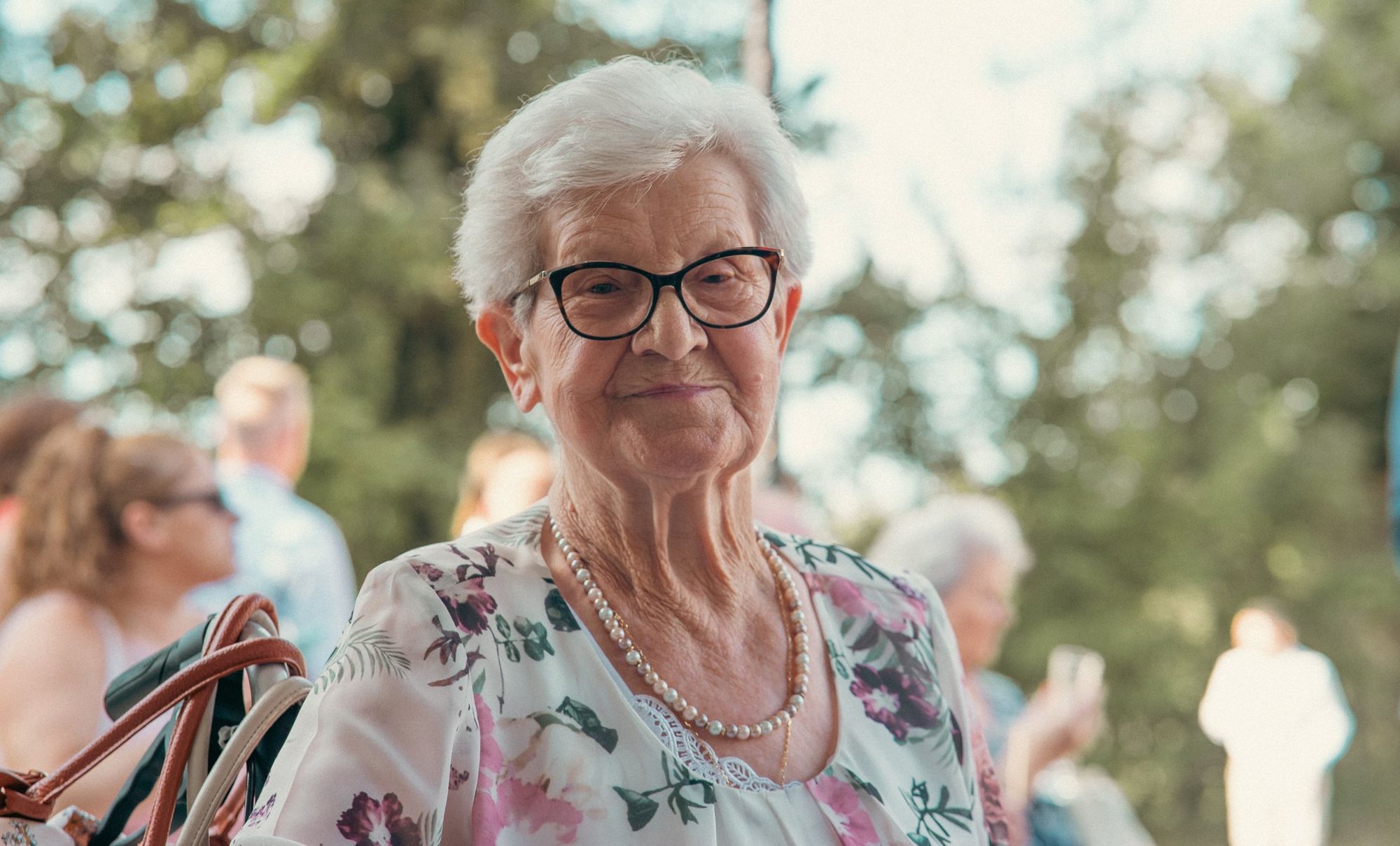 Photographe de mariage en Alsace : portrait d’une invitée souriante avec collier de perles