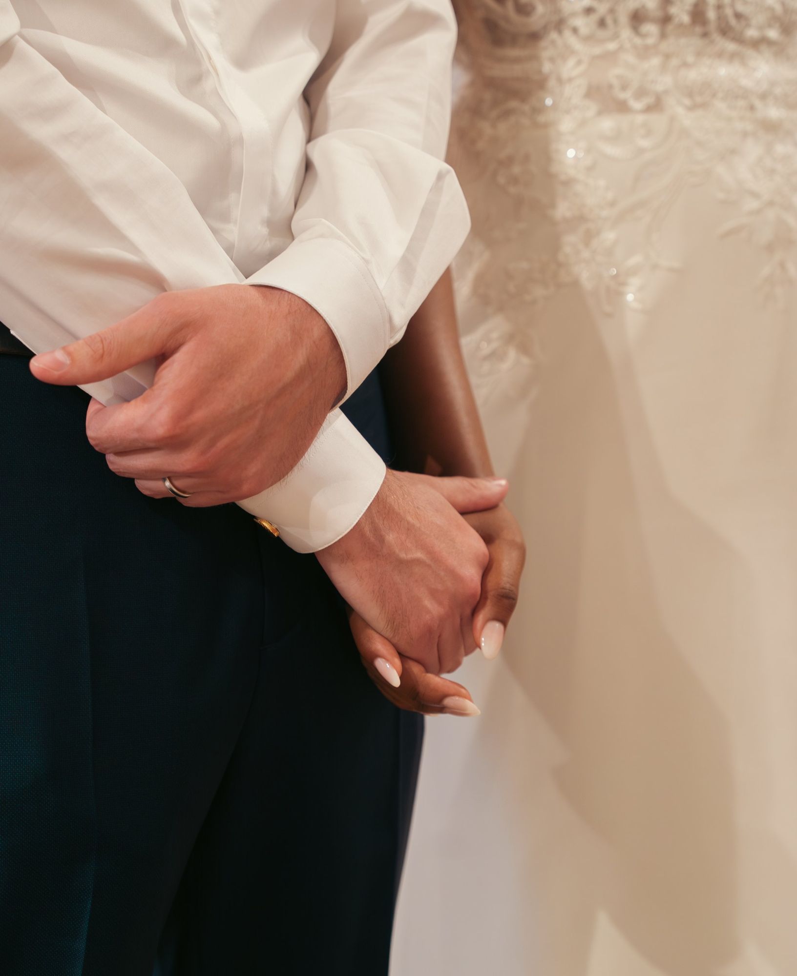 Photographe de mariage en Alsace : les mains des mariés enlacées pendant la cérémonie, détail de la robe en dentelle
