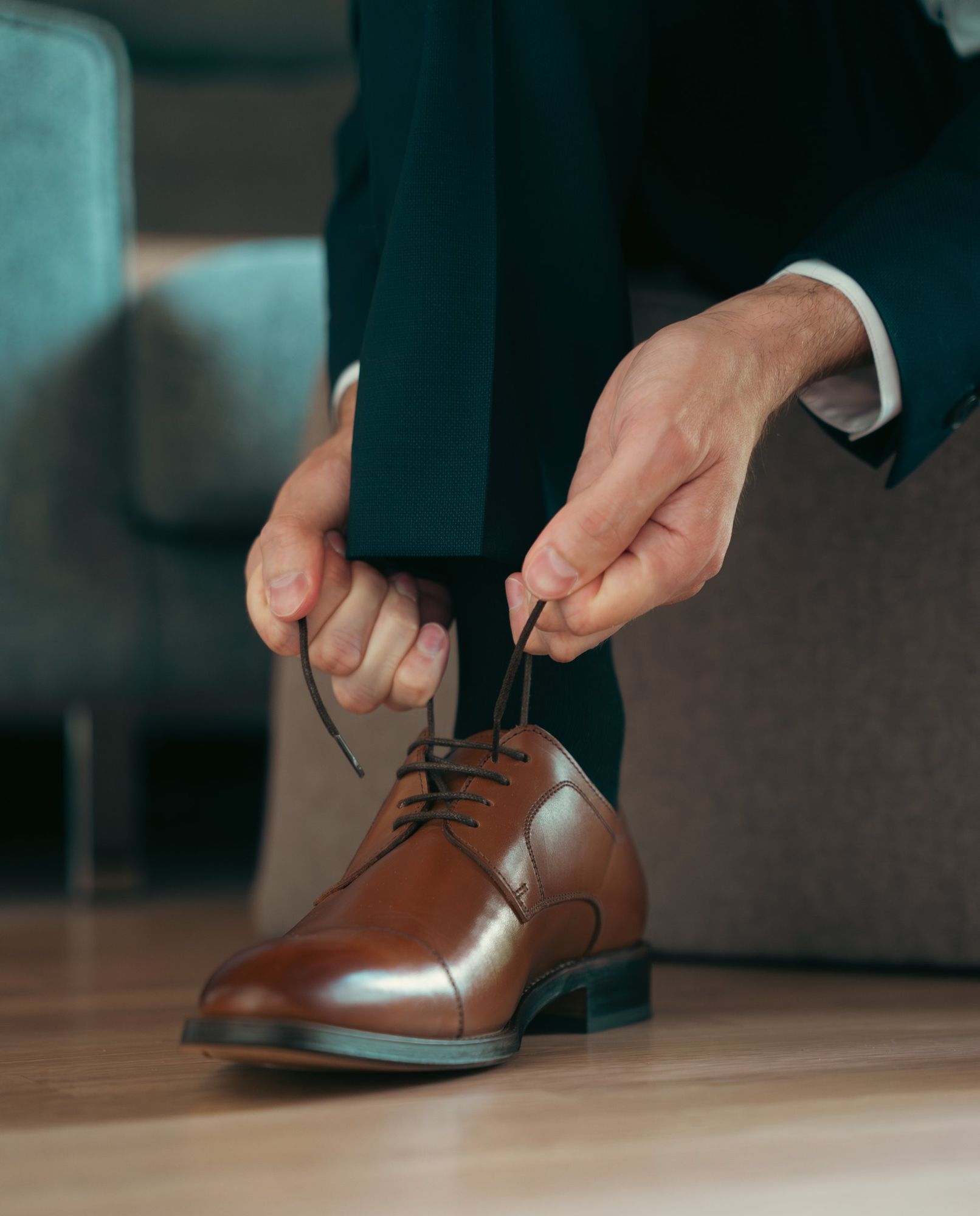 Photographe de mariage en Alsace : le marié lace ses chaussures en cuir pendant les préparatifs