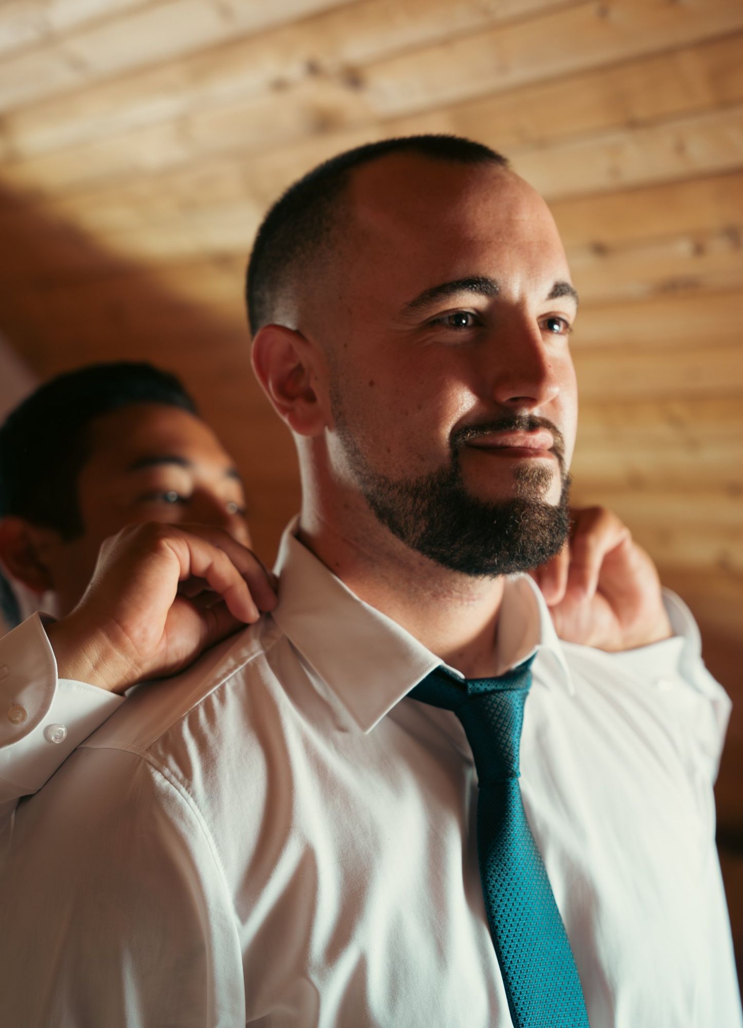Photographe de mariage à Strasbourg : le marié pendant les préparatifs, un proche ajuste son col de chemise