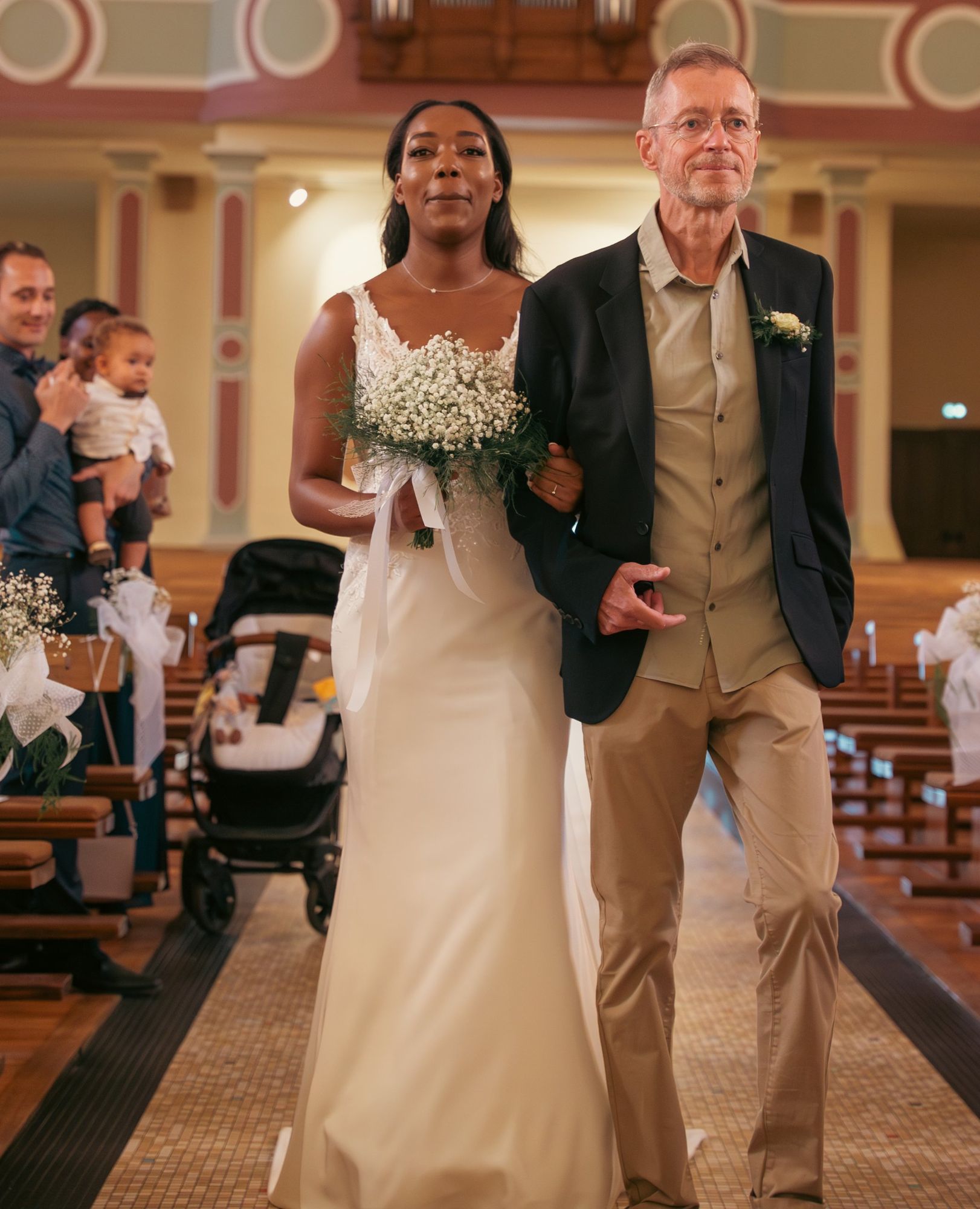 Photographe de mariage à Strasbourg : la mariée entre dans l’église au bras de son père, bouquet de gypsophile