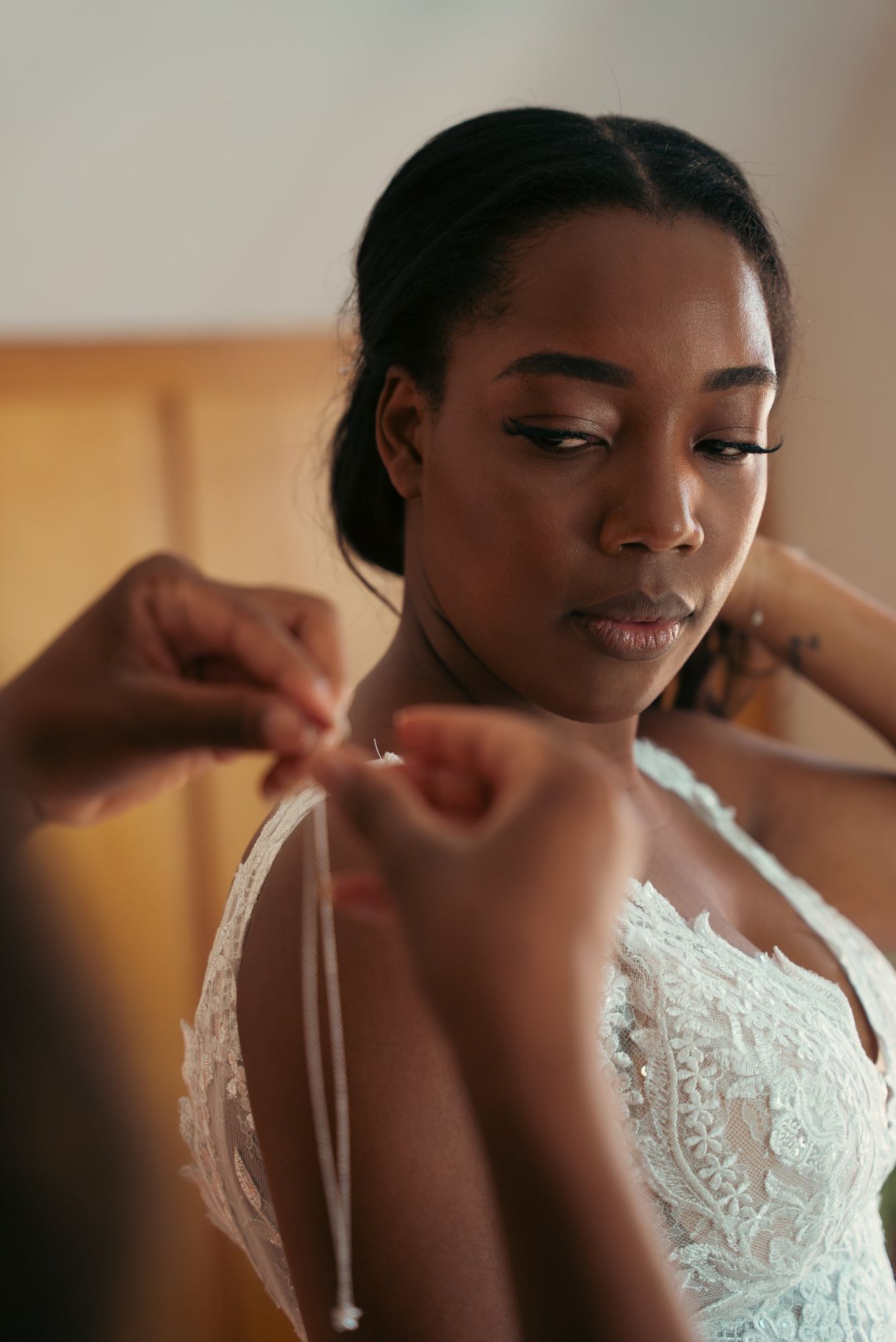 Photographe de mariage en Alsace : la mariée pendant les préparatifs, une main ajuste la bretelle de sa robe en dentelle