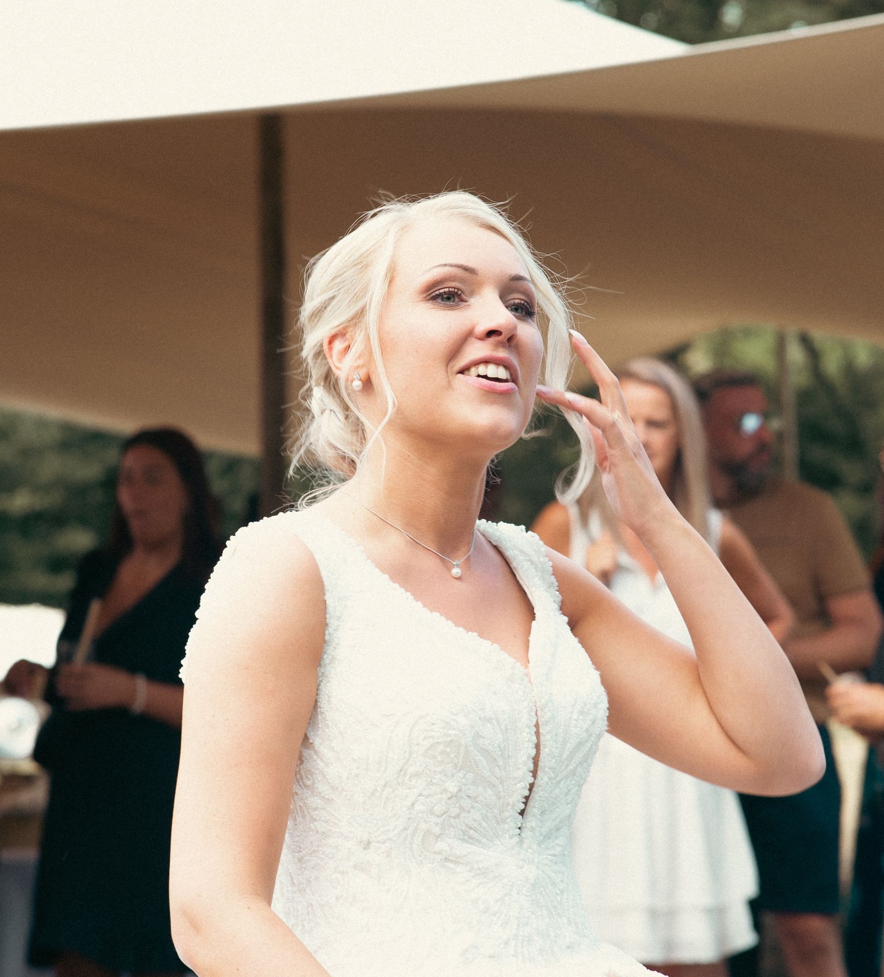 Photographe de mariage en Alsace : la mariée rit et touche une mèche de ses cheveux pendant le cocktail