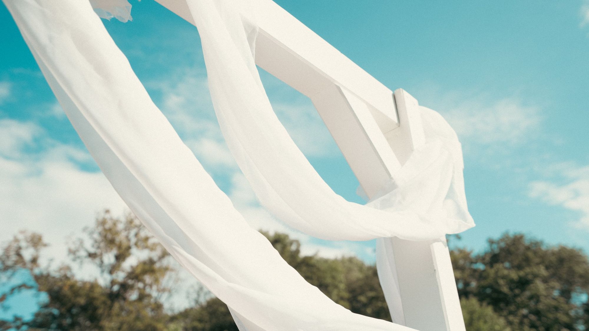 Photographe de mariage à Strasbourg : voiles blancs de l’arche de cérémonie dans le vent, ciel bleu