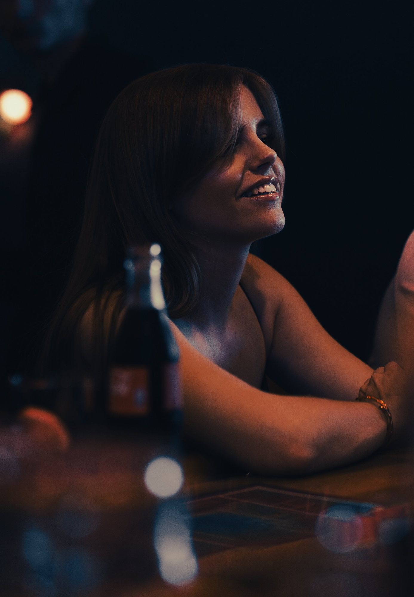 Photographe portrait à Strasbourg : une jeune femme souriante accoudée à un bar, lumière chaude