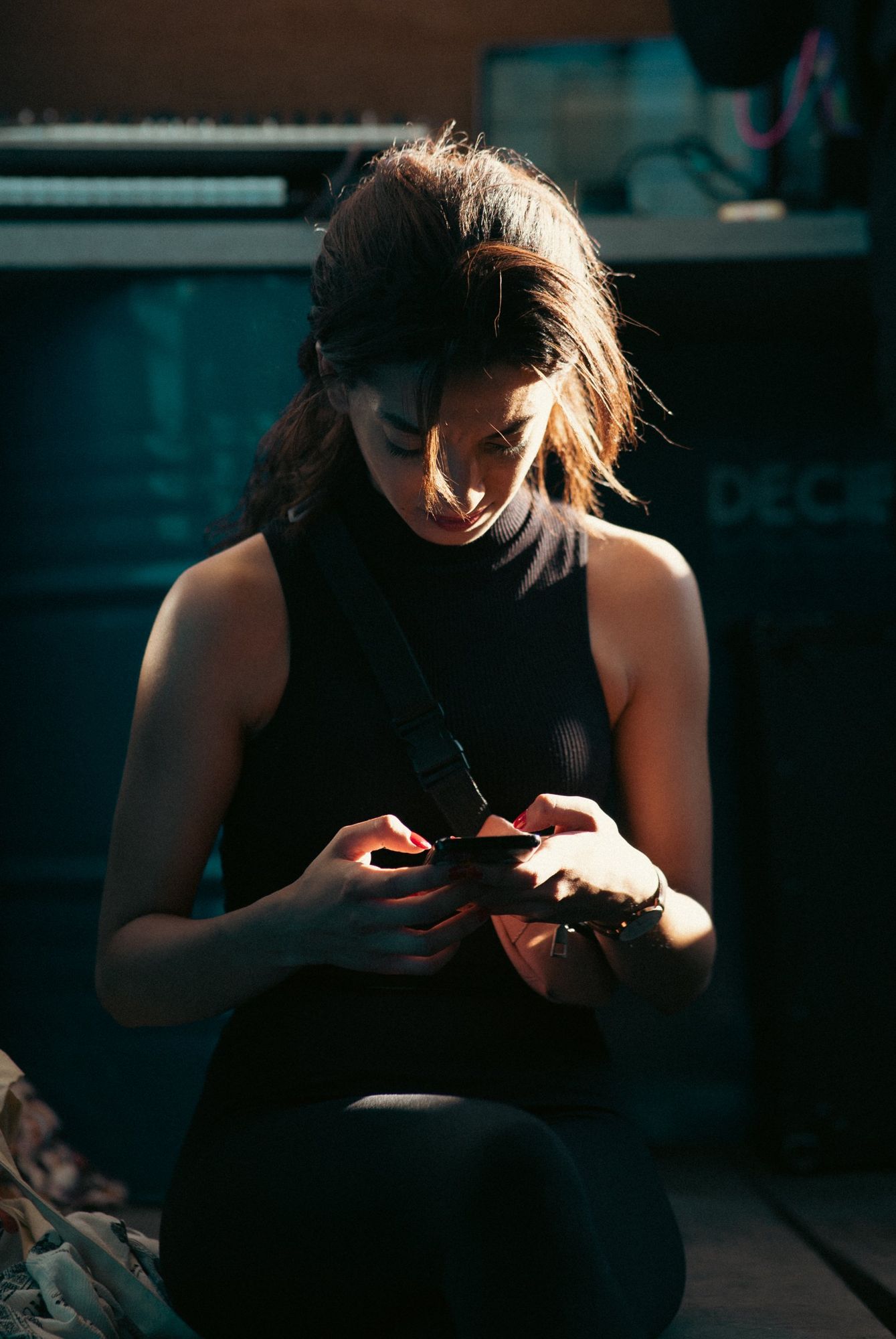 Photographe portrait à Strasbourg : jeune femme concentrée sur son téléphone, lumière rasante du soleil