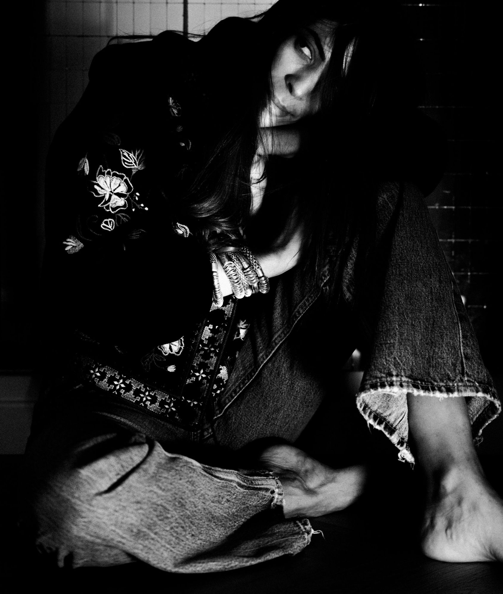Shooting photo à Strasbourg : portrait noir et blanc très contrasté d’une femme assise, veste brodée et bracelets argentés