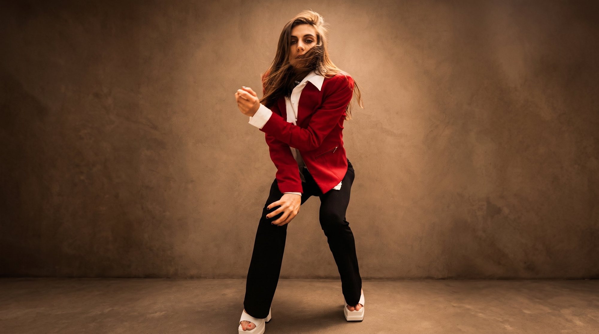 Shooting photo à Strasbourg : portrait en studio d’une danseuse en veste rouge, cheveux au vent sur fond de mur patiné