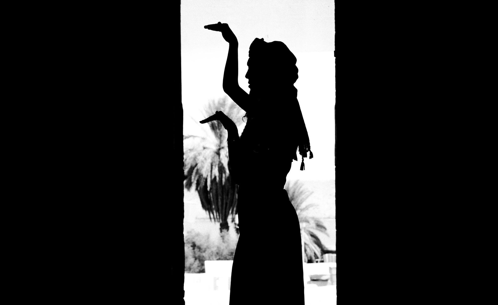 Photographe portrait : silhouette noir et blanc d’une danseuse dans l’encadrement d’une porte, palmiers en arrière-plan